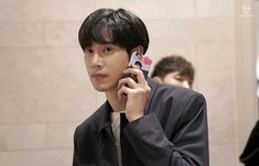 a young man holding a cell phone to his ear while standing in front of a mirror