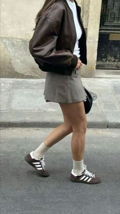 a woman walking down the street in short skirt and jacket, with her handbag on her hip