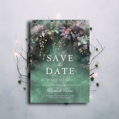 an elegant save the date card with greenery and lights on it, surrounded by branches