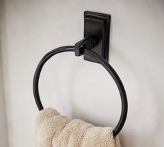 a towel hanging on the wall next to a toilet paper holder with a black ring