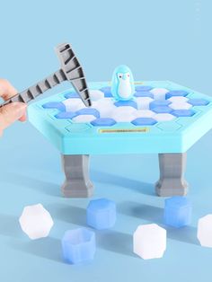 a hand is holding an ice cube game with penguins on it and snow flakes around