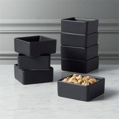 four black containers with nuts in them on a table