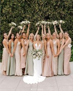 a group of women standing next to each other holding bouquets in the air with their hands up