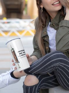 a woman sitting on the ground holding a coffee mug with her hand in her other hand