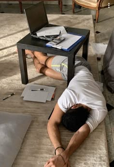 a man is laying on the floor with his head under a table and laptops