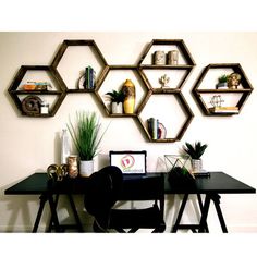 a desk with some shelves on the wall above it and plants in vases next to it