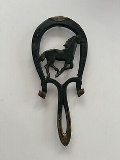 an old black metal hook with a horse on it's back and two handles