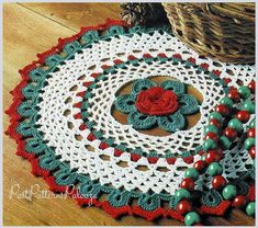 a crocheted doily with a red rose on the center and beads around it