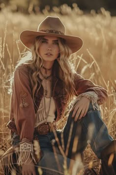 a woman wearing a cowboy hat sitting in a field