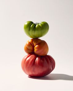 three tomatoes stacked on top of each other in the shape of a tomato, one green and one red