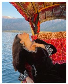 a woman is sitting on a boat in the water and looking up at her face