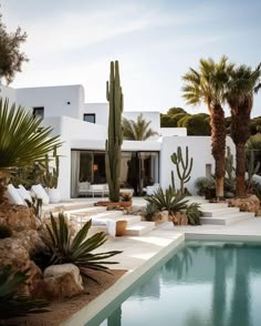 an outdoor pool surrounded by palm trees next to a white house with a large swimming pool