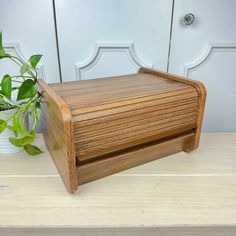 a wooden box sitting on top of a table next to a potted green plant