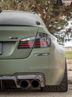 the rear end of a green sports car with exhaust pipe and tailpipes on it