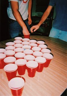 several people are standing around a table with cups on it