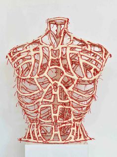 an abstract sculpture with red and white lines in the shape of a torso on top of a