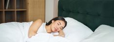 a woman laying in bed with her head on the pillow and eyes closed as she sleeps