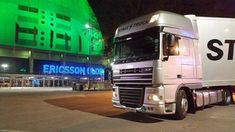 a white truck is parked in front of a building at night with neon lights on it