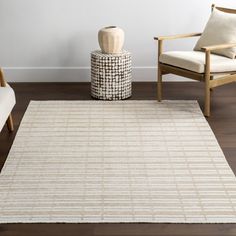 a living room area with two chairs and a rug on the floor in front of a white wall