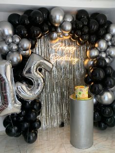 a birthday party with balloons and streamers in the shape of number five, surrounded by black and silver balloons