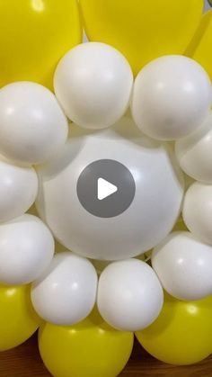 a bunch of yellow and white balloons are arranged in the shape of a circle on a table