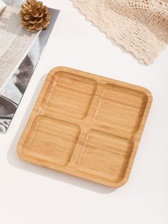 an empty bamboo tray next to a pine cone and lace on a white tablecloth