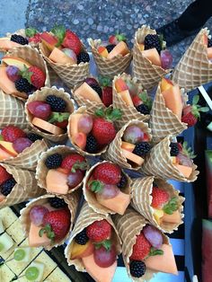 an arrangement of fruit is arranged in cones on a table with crackers and watermelon