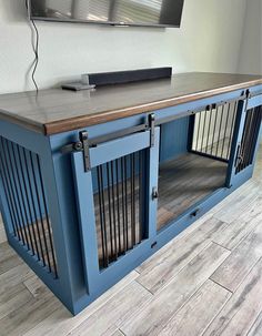 a dog kennel in front of a flat screen tv on top of a wooden table