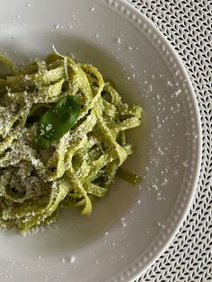 a white plate topped with pasta covered in pesto