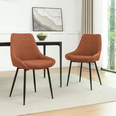 two orange chairs sitting next to each other on top of a white rug in front of a dining room table