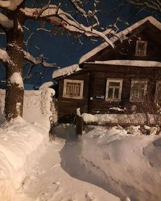 a snow covered street next to a wooden house