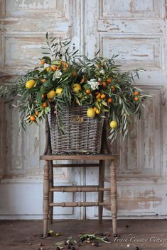 an old wooden chair with a basket full of oranges and greenery on it