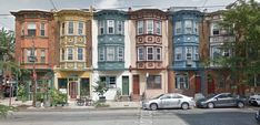 a row of multi - colored buildings on the corner of a street with parked cars