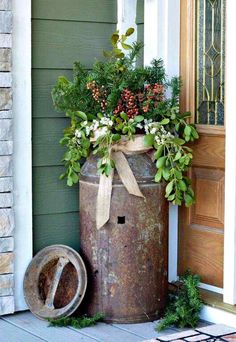 an old metal barrel with plants in it sitting on the front porch next to a door