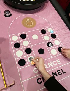 a person is playing a game on a pink table with black and white polka dots