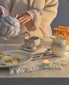 a woman pours tea from a teapot onto a plate with food on it