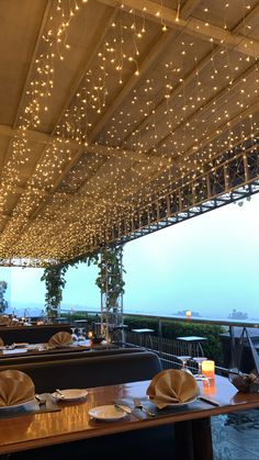 an outdoor dining area with lights strung from the ceiling and tables set up for dinner