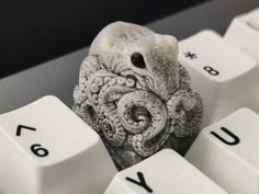 an octopus figurine sitting on top of a computer keyboard with the letters u and y below it