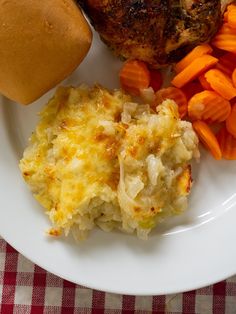 a white plate topped with meat, potatoes and carrots next to a baked potato