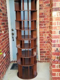 a tall brown shelf sitting next to a brick wall on the side of a building