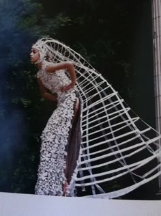 a woman in a white dress is standing on a ledge