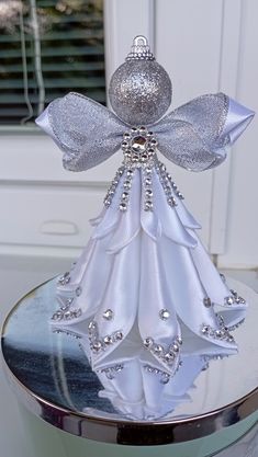 a white ornament on top of a table with silver ribbon and beading