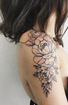 the back of a woman's shoulder with flowers and leaves tattooed on her arm