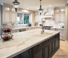 a large kitchen with marble counter tops and white cabinets, along with an island in the middle