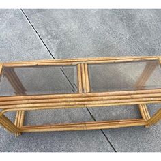 a coffee table made out of bamboo with glass top and bottom shelf on concrete ground