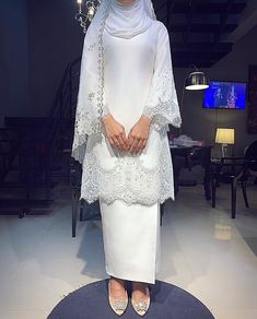 a woman standing in front of a mirror wearing a white outfit