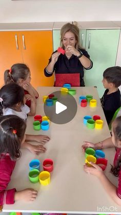 a group of children sitting around a table playing with cups