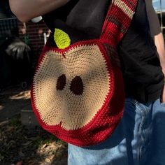 a crocheted apple bag with a green leaf sticking out of it's mouth