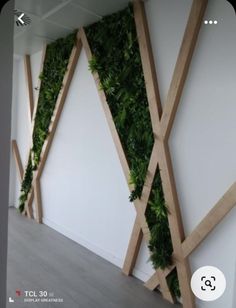 an office with white walls and green plants on it's wall dividers that are made out of wood planks