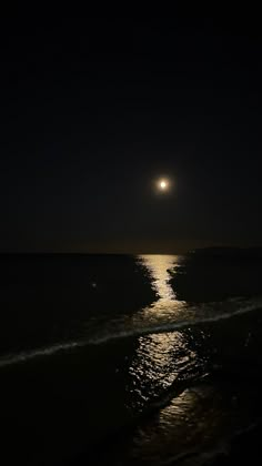 the moon is shining over the ocean at night